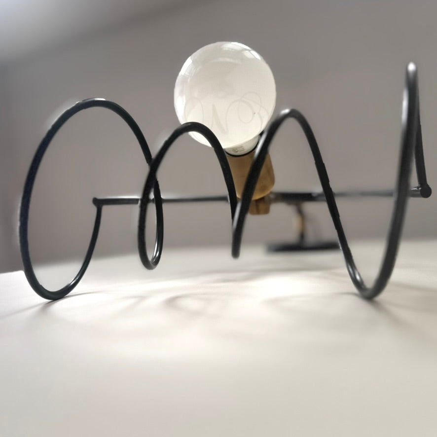 Decorative sconce with spring shaped base with medium base brass socket cup.