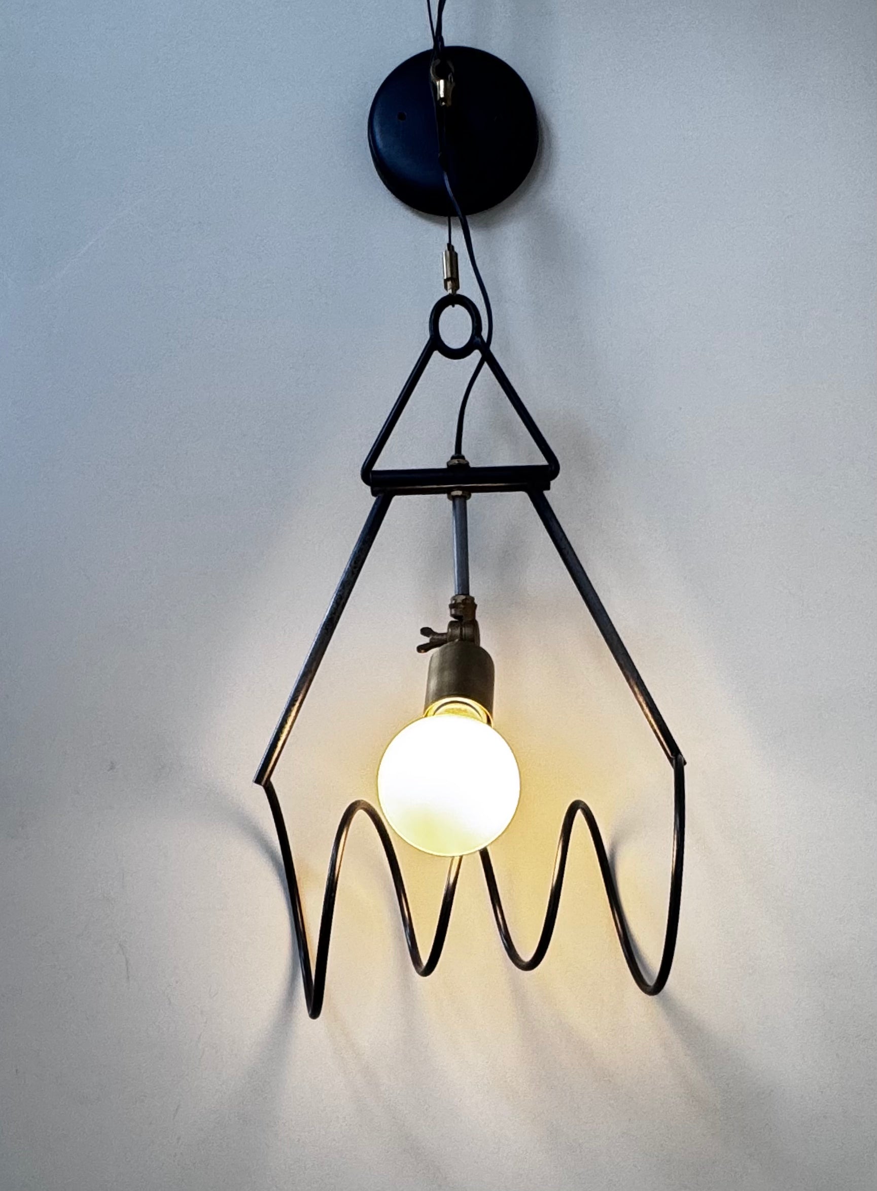 "Limited-edition sculptural wall sconce in steel and brass with black powder coat, hot wax finish, and polished brass accents."

