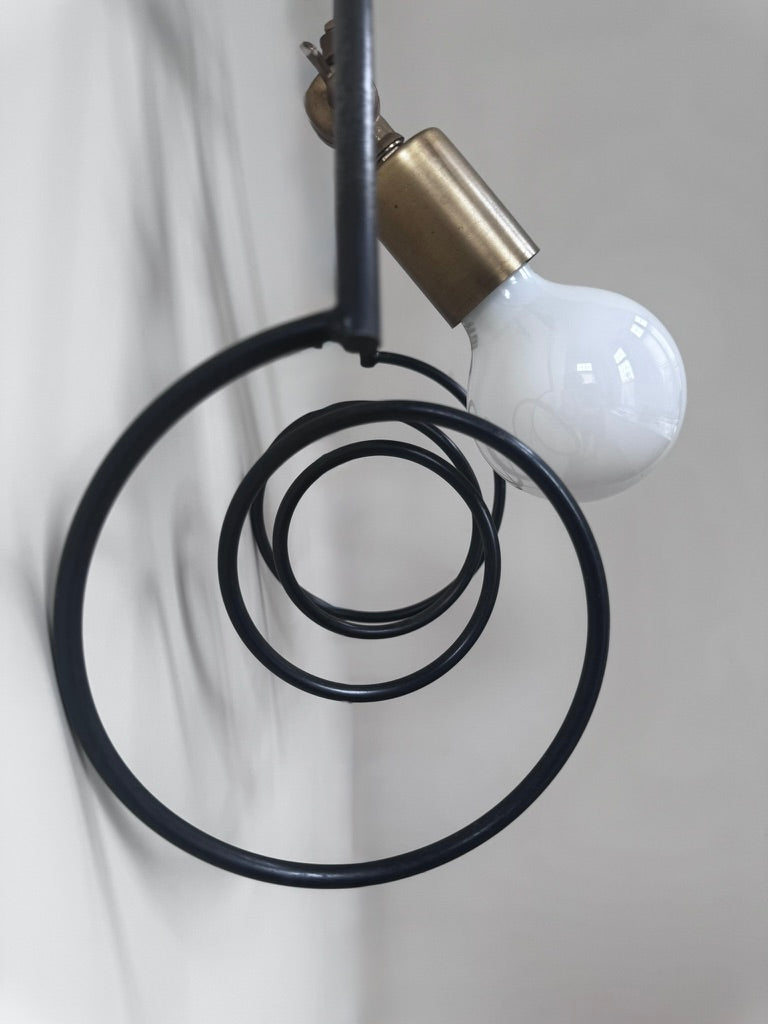 Polished brass detail on modern steel coil wall sconce with black powder coating and hot wax finish.